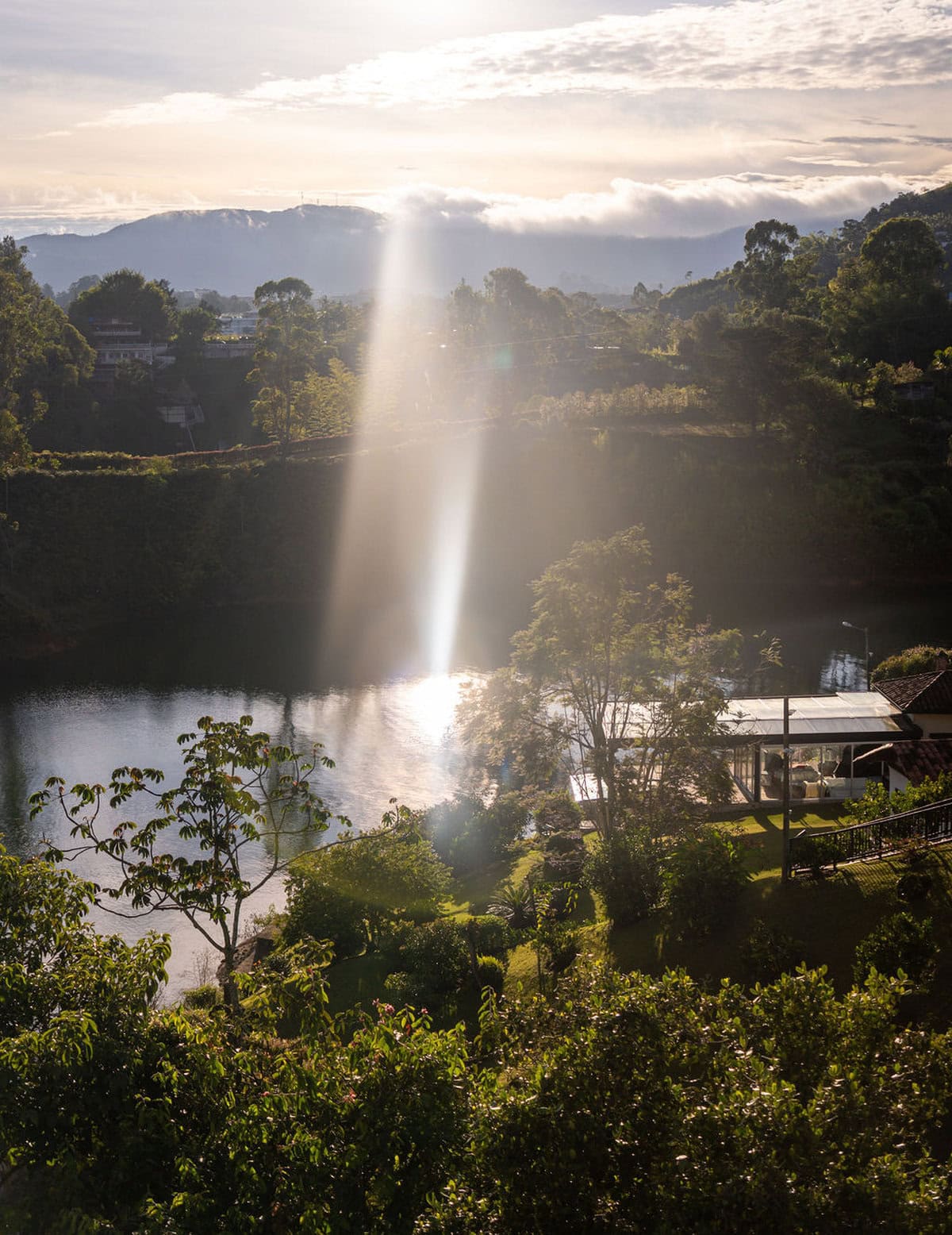 Serene landscape at Finca Conejo Blanco with water reflection, mountains, and lush greenery.