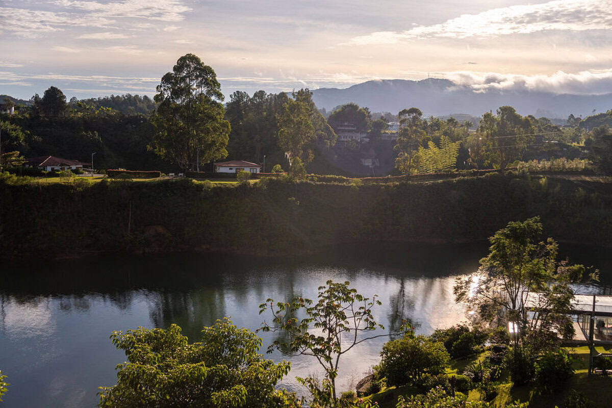 Scenic view of Finca Conejo Blanco with lush greenery and tranquil water body in a rural setting.