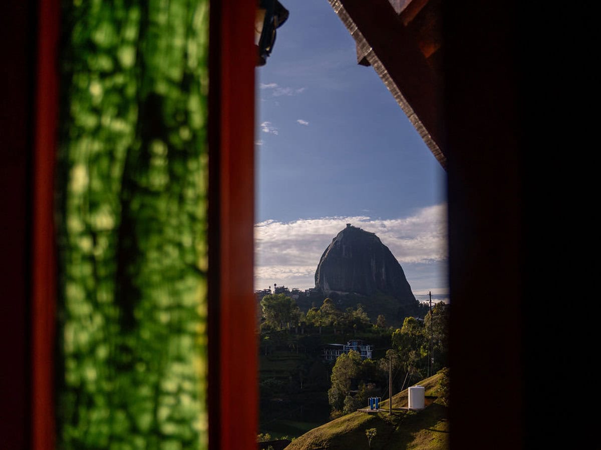 Panoramic view of Sugarloaf Mountain through a rustic window at Finca Conejo Blanco, showcasing scenic landscapes and lush greenery.