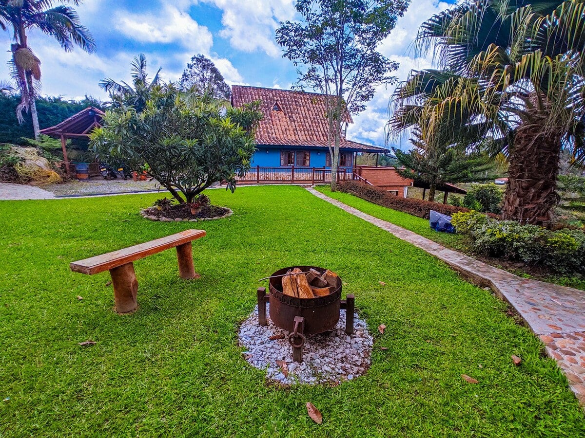 Burned wood outdoor fire pit at Finca Conejo Blanco, lush garden with vibrant green grass and trees.