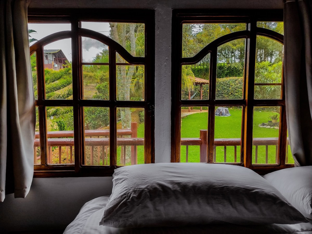Rustic wooden window view of lush green garden and outdoor space at Finca Conejo Blanco.
