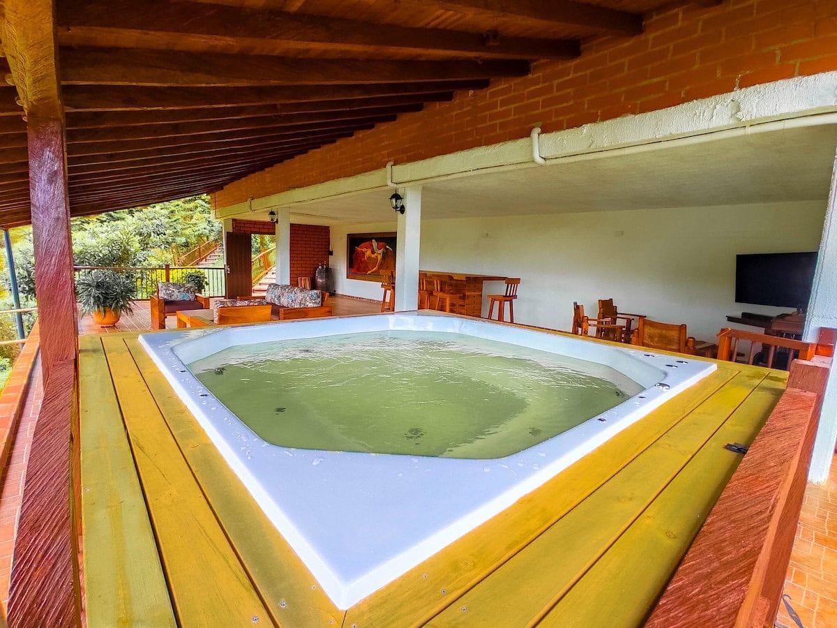 Hot tub on the covered terrace at Finca Conejo Blanco with outdoor seating and lush greenery in the background.