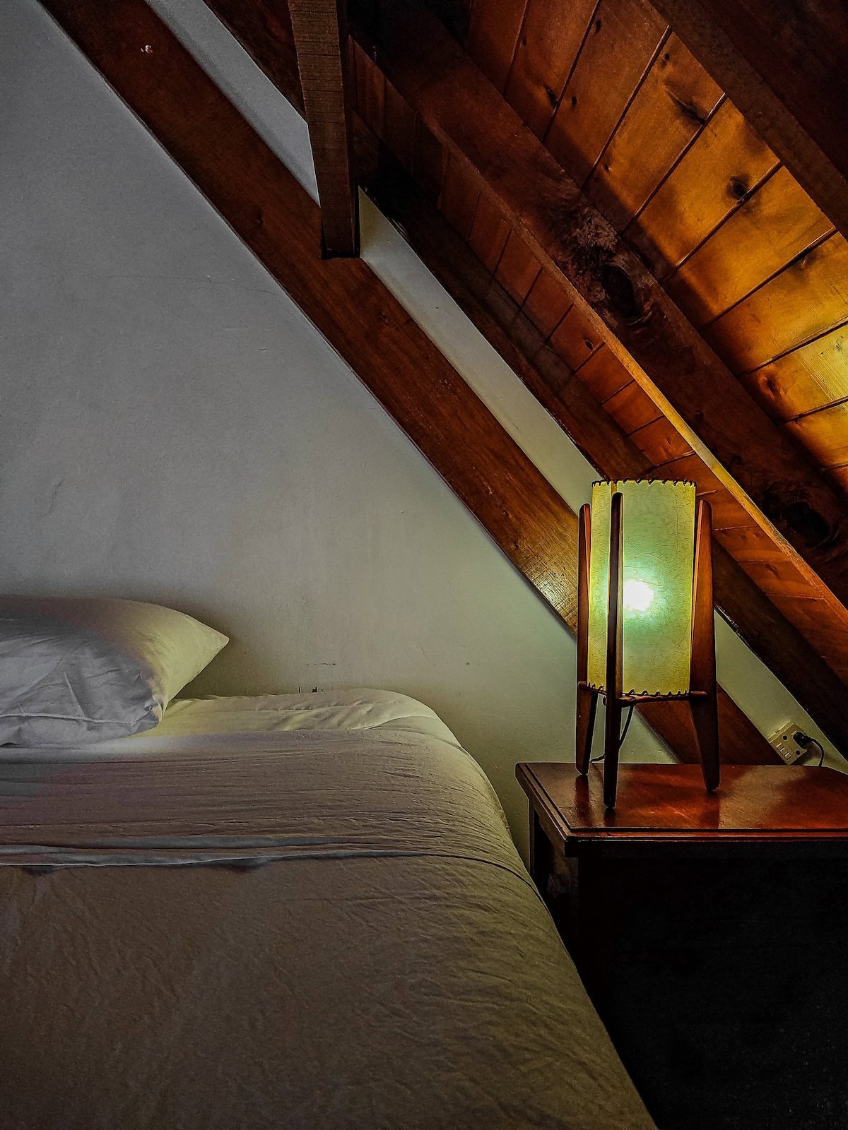 Cozy bedroom with wooden ceiling and bedside lamp in Finca Conejo Blanco.